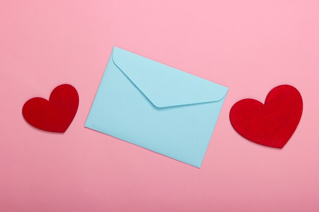 Enveloppe avec des coeurs rouges Saint-Valentin sur pastel rose