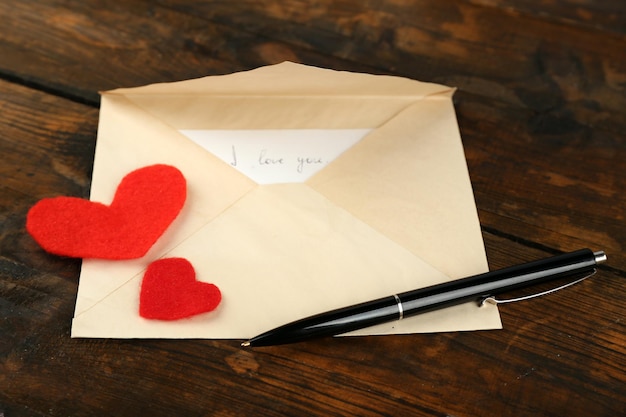 Enveloppe avec coeurs et stylo sur fond de table en bois rustique