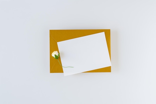 Enveloppe dorée avec carte et roses sur fond blanc