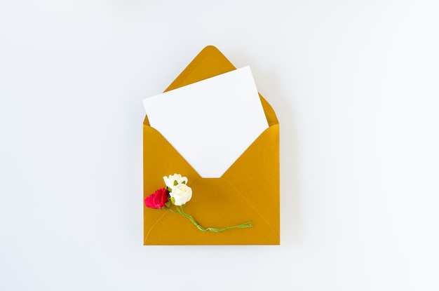 Enveloppe dorée avec carte et roses sur fond blanc