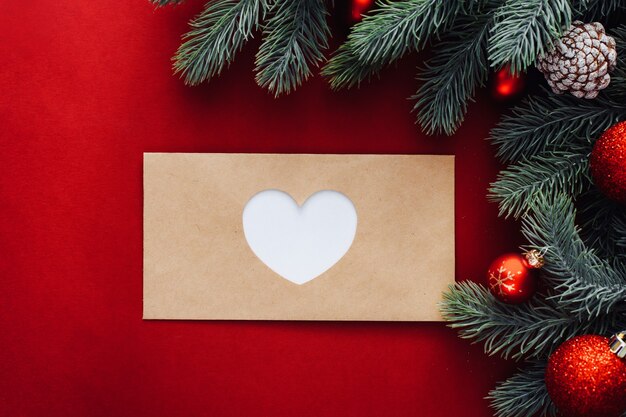 Une Enveloppe Fermée Avec Un Cœur Découpé Dessus à Côté De Branches Et Décorations De Noël, Boules.