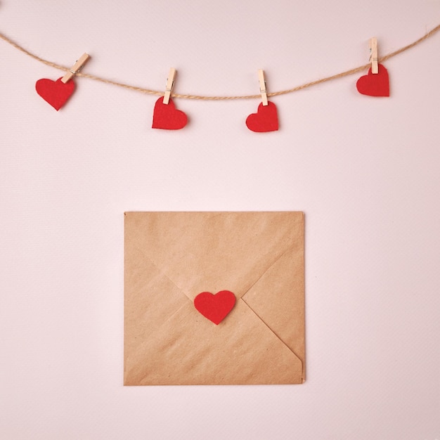 Enveloppe festive et valentines épinglés à une corde sur fond clair