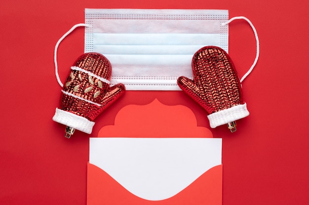 Enveloppe de lettre rouge de Noël avec un espace pour le texte sur fond rouge ainsi qu'un masque médical comme symbole de sécurité