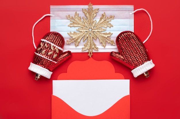 Enveloppe de lettre rouge de Noël avec un espace pour le texte sur fond rouge ainsi qu'un masque médical comme symbole de sécurité