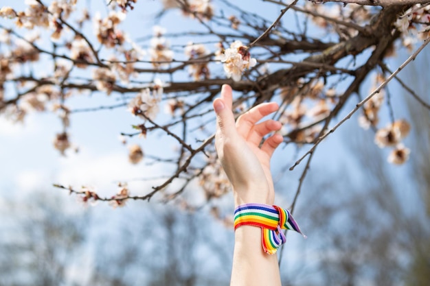 Enveloppé à la main dans du ruban lgbt arc-en-ciel sur fond d'arbre en fleurs