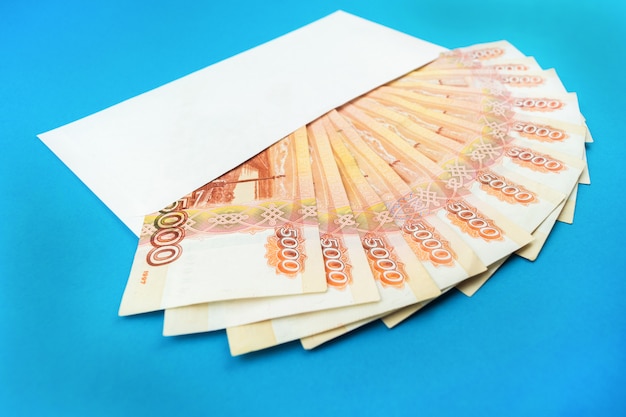 Photo enveloppe avec monnaie russe sur fond bleu