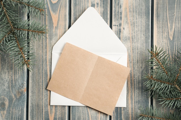 Enveloppe de Noël ouverte blanche sur fond de bois gris avec carte de voeux en papier kraft vierge Espace de copie Vue de dessus