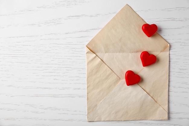 Enveloppe ouverte vierge avec petits coeurs sur fond de bois