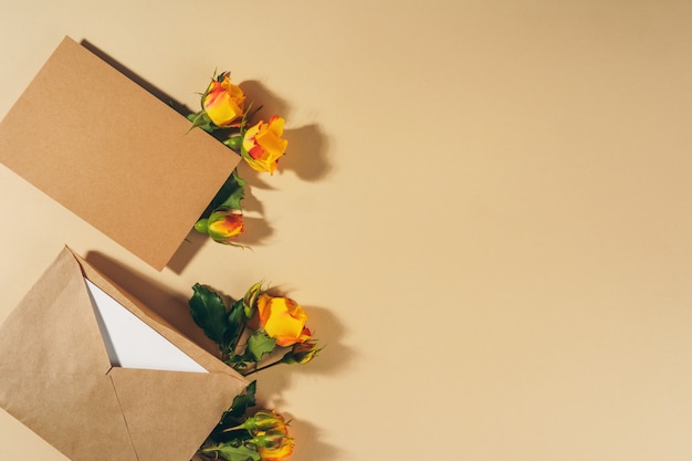 Enveloppe en papier artisanal avec des roses jaunes sur une surface beige