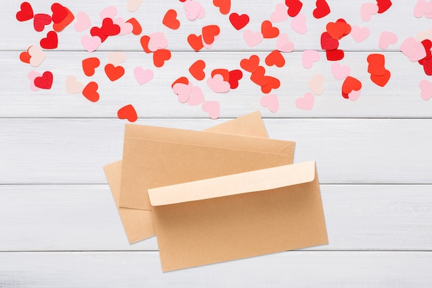 Photo enveloppe de papier craft avec coeur rouge dessus, sur bois blanc