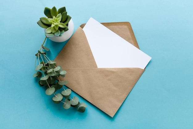 Une enveloppe en papier kraft et une carte postale vierge blanche sur fond bleu Préparation de la carte postale