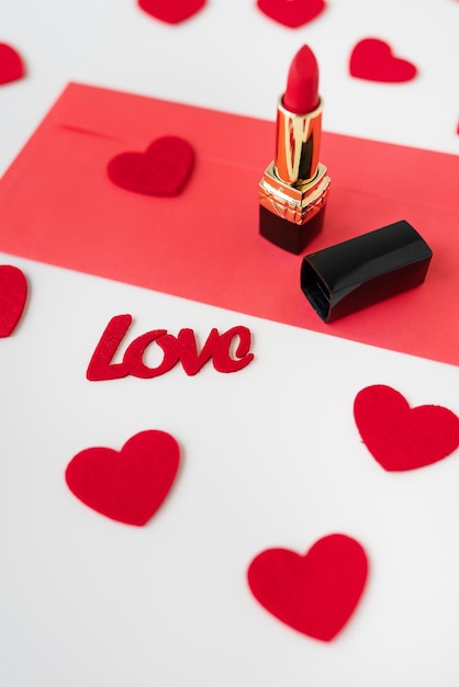 Une enveloppe rouge avec du rouge à lèvres rouge sur fond de petits coeurs rouges Le concept de la maison de vacances 14 février Saint Valentin