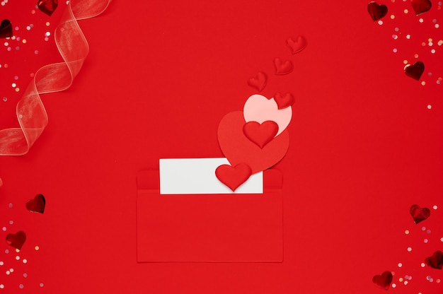 Enveloppe rouge avec lettre d'amour sur fond rouge avec de nombreux coeurs autour. Des coeurs sortent de l'enveloppe. Les coeurs s'envolent de l'enveloppe. Lettre d'amour