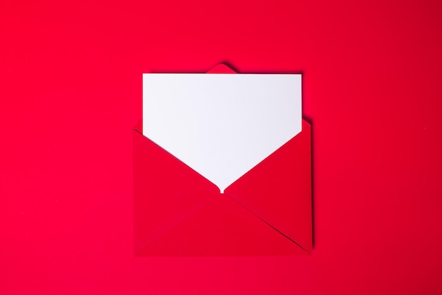 Photo enveloppe rouge maquette avec du papier blanc propre à l'intérieur sur un gros plan de fond rouge