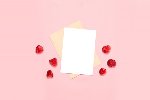 Enveloppe vide avec une feuille de papier, décorée de framboises indigènes, vue de dessus