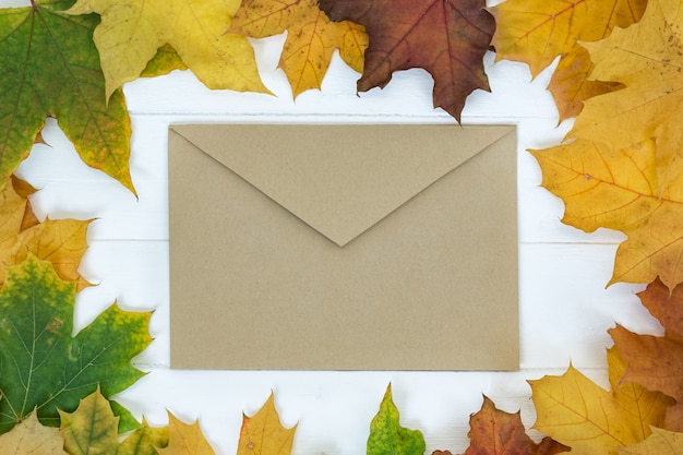 Enveloppe vintage marron sur surface blanche dans le cadre de feuilles d'automne