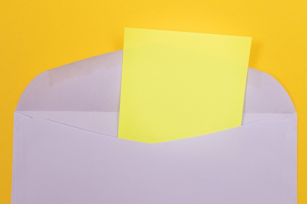 Enveloppe violette avec une feuille de papier jaune vierge à l'intérieur