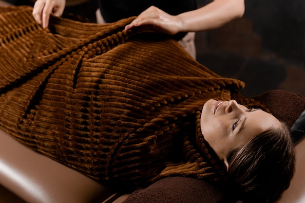 Enveloppement complet du corps après massage au chocolat. Traitement de beauté pour modèle féminin au spa.