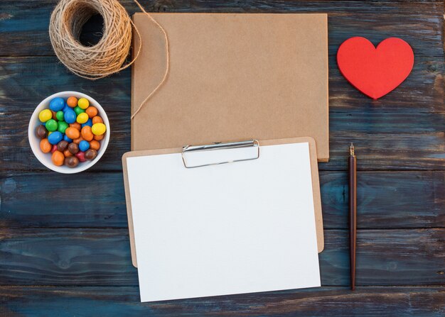 Enveloppes d'artisanat vides et feuille de calligraphie, corde, doux, stylo à encre, coeur rouge sur fond en bois