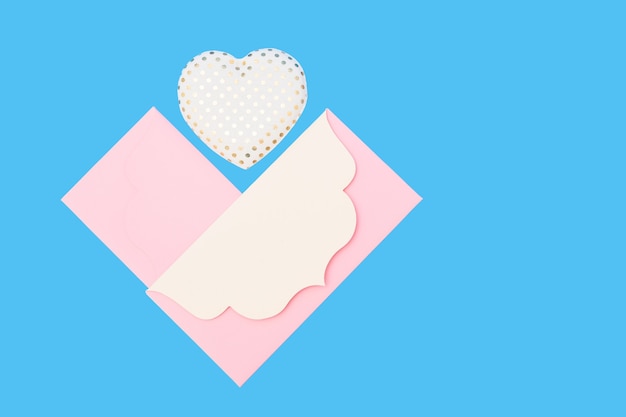 Photo enveloppes en papier rose et décoration en forme de coeur sur fond bleu dans le style de la saint-valentin