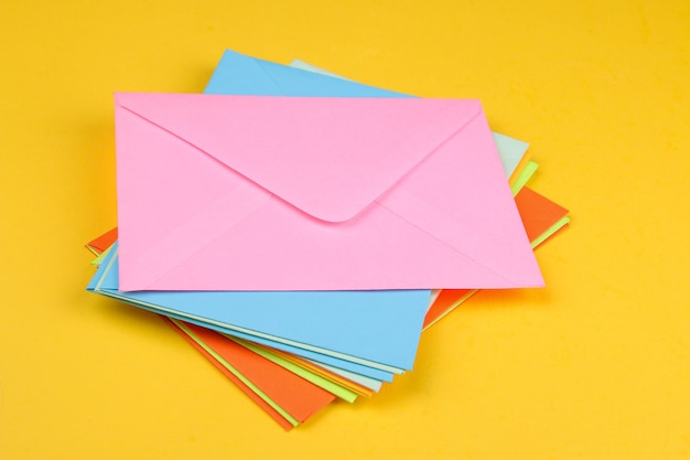 Enveloppes postales multicolores empilées sur un fond jaune vif concept de courrier ou de livraison