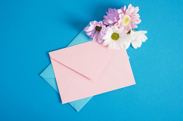 Enveloppes roses et bleues et fleurs sur fond bleu copie espace maquette