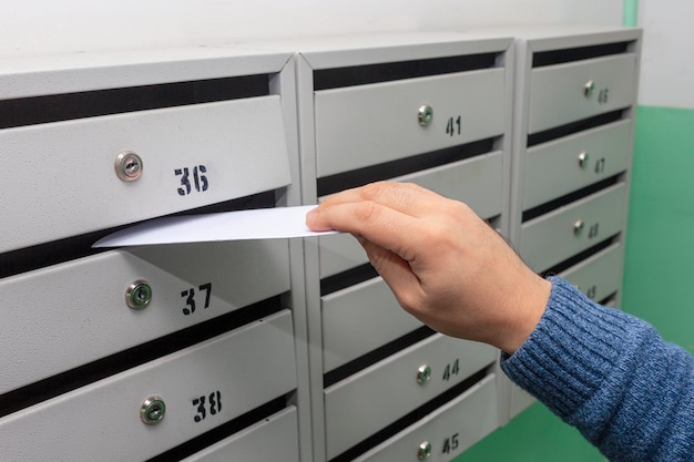 Envoi de courrier, un homme met une lettre dans la boîte aux lettres. Placer des lettres dans la boîte aux lettres d'un immeuble, gros plan. Russie