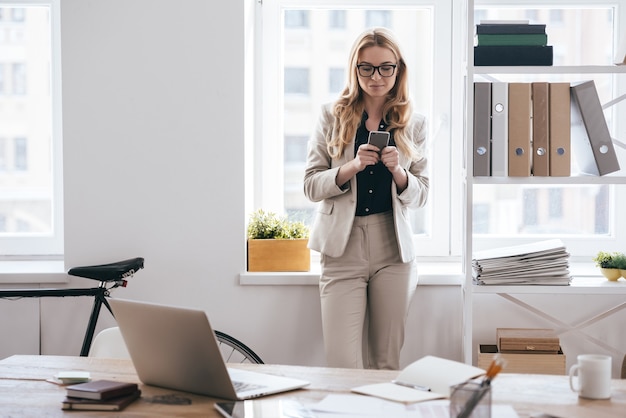 envoyer un message d'affaires par SMS. jeune femme d'affaires en vêtements décontractés intelligents en tapant quelque chose