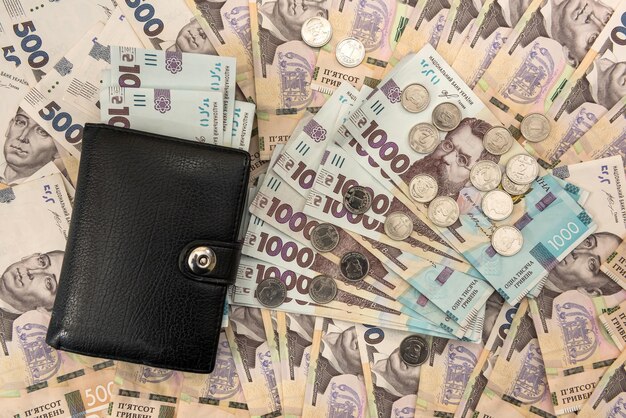 L'épais portefeuille des hommes noirs chargé d'argent se trouve dans le contexte de l'argent hryvnia ukrainien. Concept d'économiser de l'argent