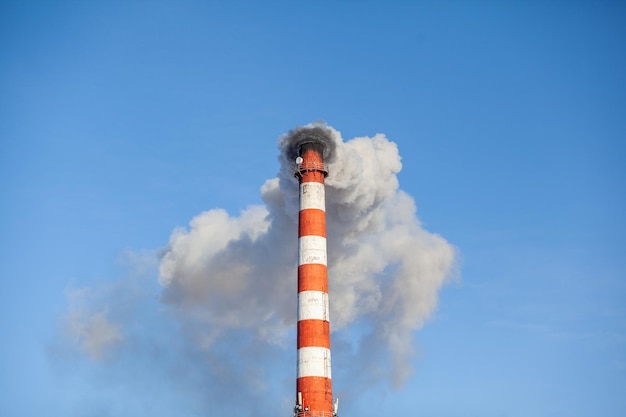 Une épaisse fumée blanche s'échappe de la cheminée de la chaufferie. Fumée contre le ciel bleu. La pollution de l'air.