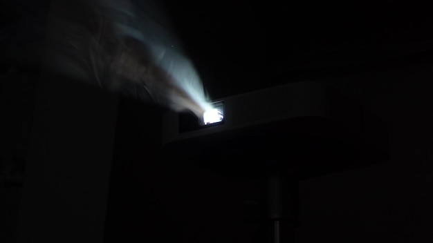 Une épaisse fumée brille dans les faisceaux des projecteurs Un projecteur de film à domicile brille sur des bouffées de vapeur denses Concept de fumée et de lumière