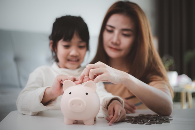 Epargne Familiale. Mère enseignant à sa petite fille comment économiser de l'argent en tenant une tirelire