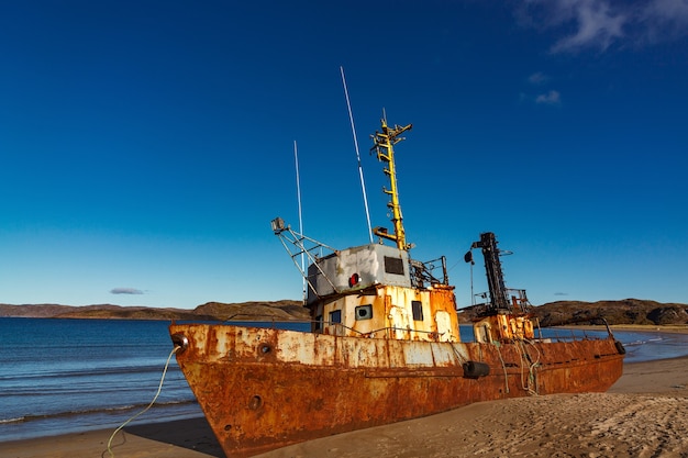 Une épave sur une plage de sable à marée basse dans la baie de Teriberskaya. Grand Nord, mer de Barents en Russie.