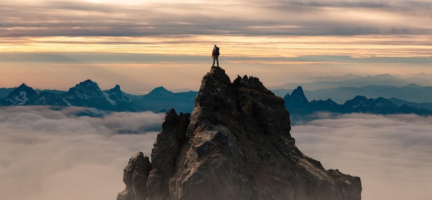 Photo epic adventure composite of man hiker au sommet d'une montagne rocheuse. ciel coucher de soleil spectaculaire. pic de rendu 3d. paysage de fond d’amérique du nord. notion de liberté.