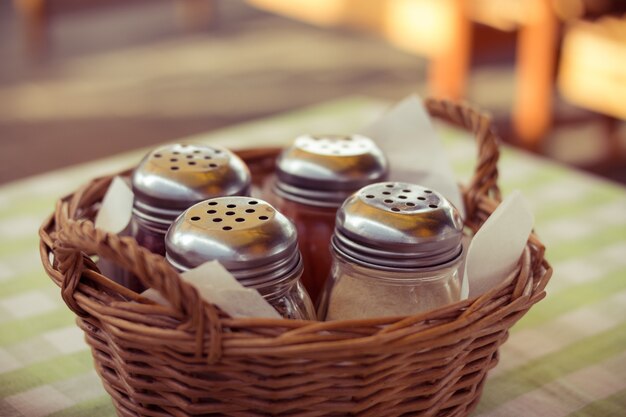 Épices En Bouteilles De Verre Dans Un Panier En Osier Sur La Table à Café. Déjeuner En Plein Air Un Jour D'été