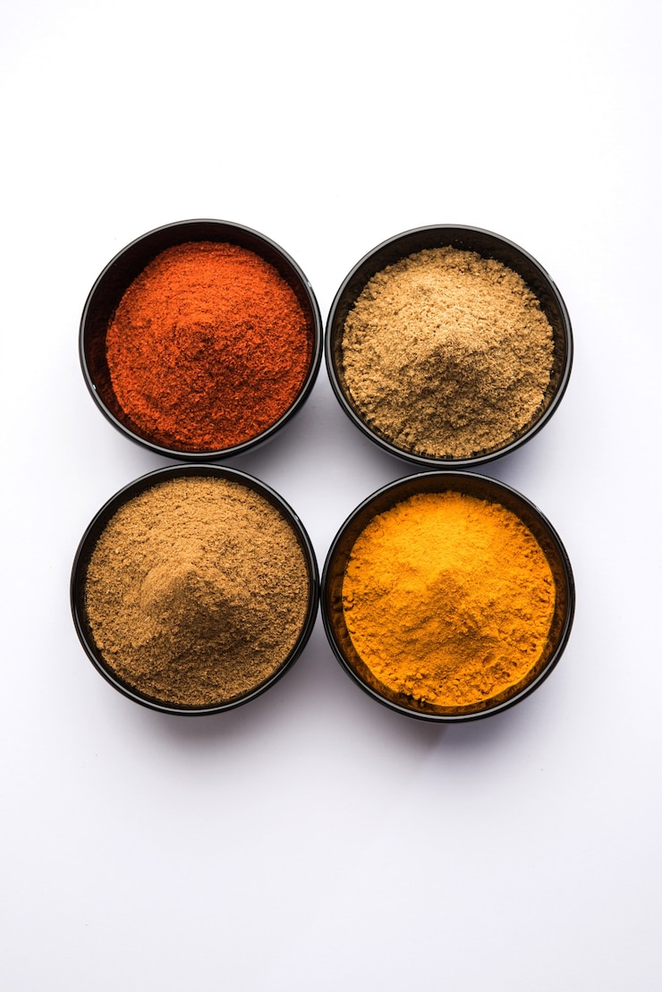 Photo épices colorées indiennes. photo de groupe de quatre épices indiennes de base comme le piment rouge cru, le curcuma, la coriandre et la poudre de cumin. mise au point sélective