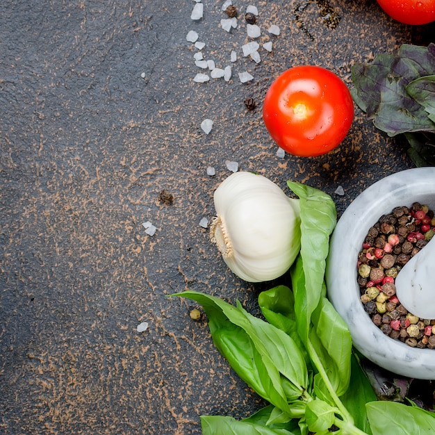 Epices dans un mortier de pierre, basilic vert et tomates