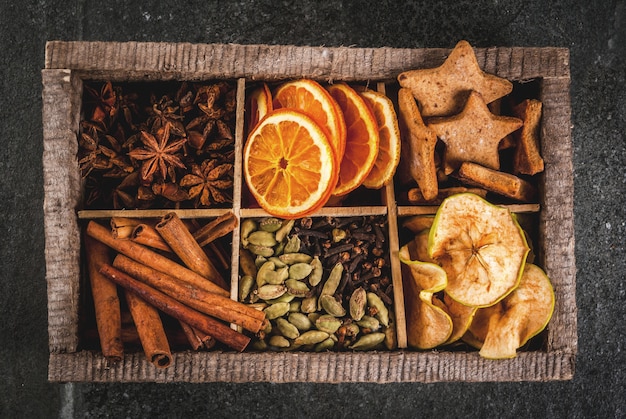 Épices De Noël Pour La Pâtisserie, Cocktails, Vin Chaud, Avec Biscuits De Pain D'épice (étoiles) - Pomme Séchée, Orange, Cardamome, Clou De Girofle, Cannelle, Anis. Vieille Boîte En Bois, Table En Pierre Noire. Copie Vue De Dessus De L'espace