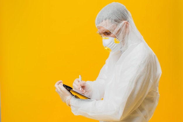 épidémiologiste dans un masque et un costume hazmat sur l'écriture du mur jaune