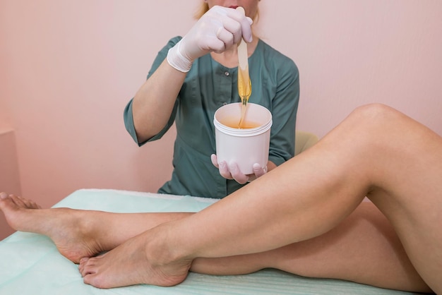 Photo Épilation au studio de luxe du spa épilation des jambes de la femme avec le sucre sucre chaud