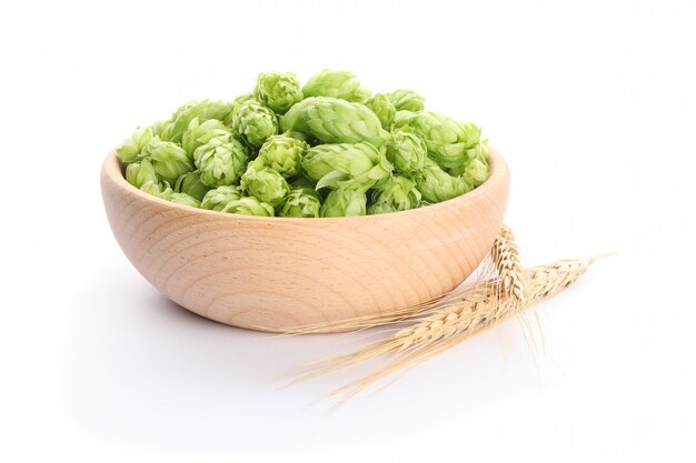 Épillets et bol en bois avec houblon isolé sur blanc