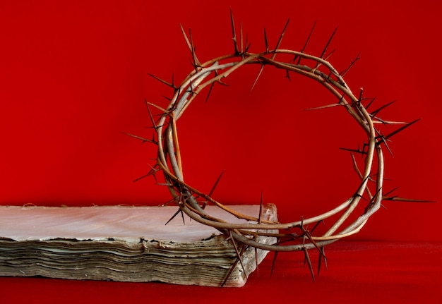 Épines de la couronne et vieille bible ou livre sur fond rouge, espace de copie.