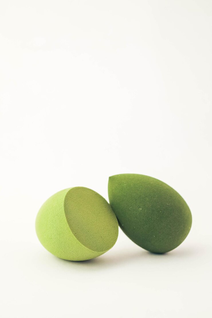 Des éponges de maquillage vertes sur un fond blanc Une composition minimaliste présentant des outils de beauté pour le fond de teint parfait pour les thèmes de soins de la peau et de cosmétiques