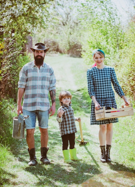 Épouse et mari avec fils plantant dans le potager deviennent agriculteurs biologiques un couple avec enfant ...