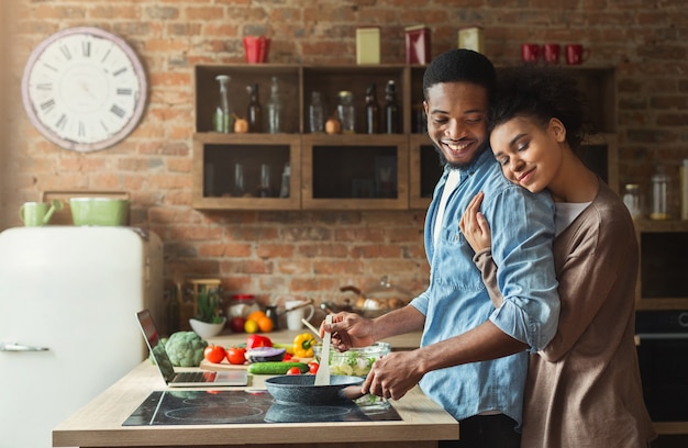 Épouse noire aimante et mari préparant le dîner. Héhé, cuisine végétarienne dans la cuisine loft