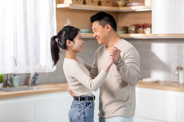 Épouses asiatiques heureusement mariées dansant la valse à la cuisine