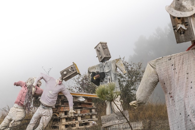 Des épouvantails avec des boîtes en bois comme têtes et vêtus de haillons au milieu du brouillard hivernal.