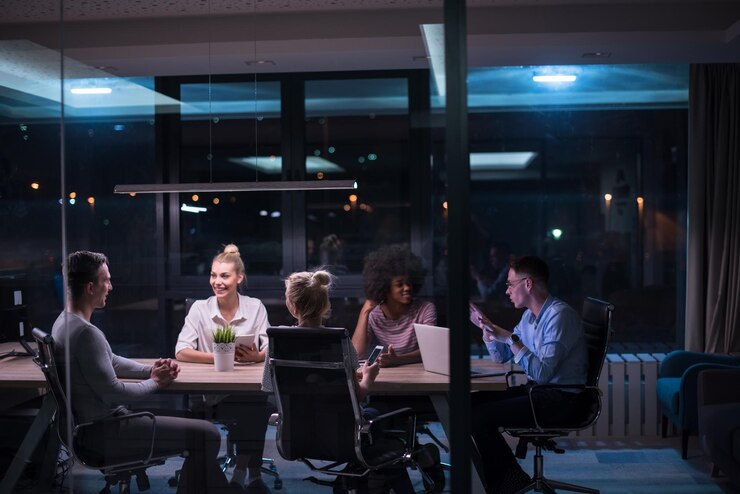 Équipe d'affaires multiethnique en démarrage lors d'une réunion dans un brainstorming intérieur de bureau de nuit moderne, travaillant sur un ordinateur portable