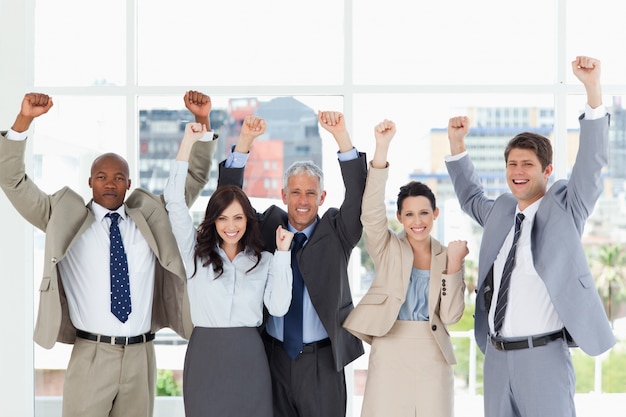 Équipe des affaires souriant debout debout avec les bras levés dans le succès