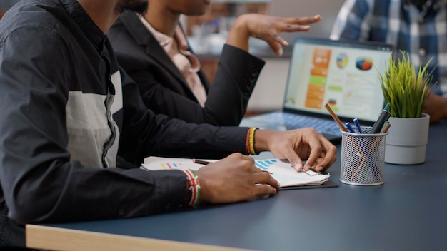 Une équipe afro-américaine de personnes se réunissant pour réfléchir à des idées sur la collaboration de projets avec des tableaux financiers sur ordinateur portable. Gens d'affaires assistant à une discussion d'information avec des collègues. Prise de vue à main levée.